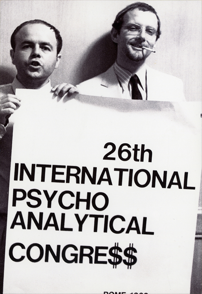 Elvio Fachinelli e Berthold Rothschild durante il "controcongresso", con il cartello "26th International Psycho Analytical Congre$” (© Lisetta Carmi 1969, Collezione privata)
