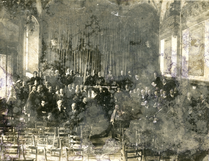 Studiosi a congresso ai primi del '900. Al centro del tavolo, in piedi, in senso orario, Giulio Cesare Ferrari, Edouard Claparède e Auguste Ley; a destra verso il muro, con un foglio in mano, probabilmente Cesare Colucci